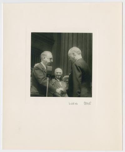 Chief Justice Vinson in handshake with John W. Snyder, with President Truman standing behind
