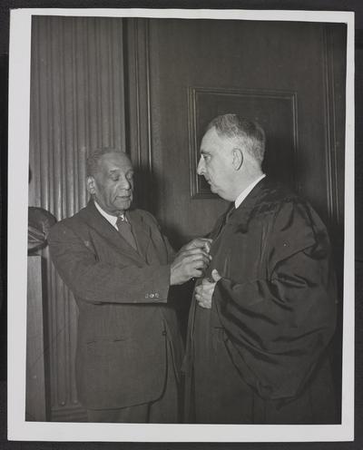 Messenger, Robert Marshall assists Chief Justice Vinson don his robe on the opening day of Court