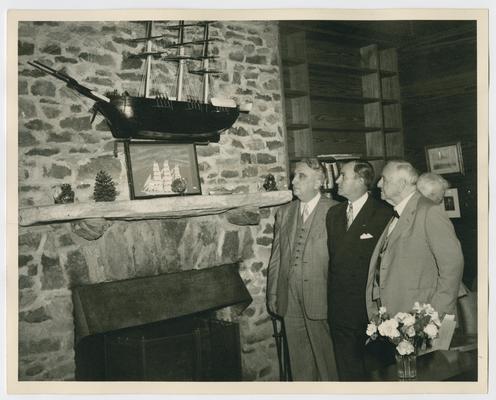 Chief Justice Vinson, left, with Governor M.E. Thompson and Josephus Daniels looking at ship hanging above a fireplace. Shot 1