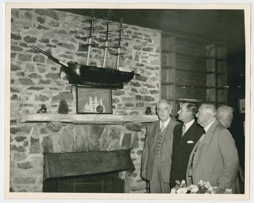 Chief Justice Vinson, left, with Governor M.E. Thompson and Josephus Daniels looking at ship hanging above a fireplace. Shot 2