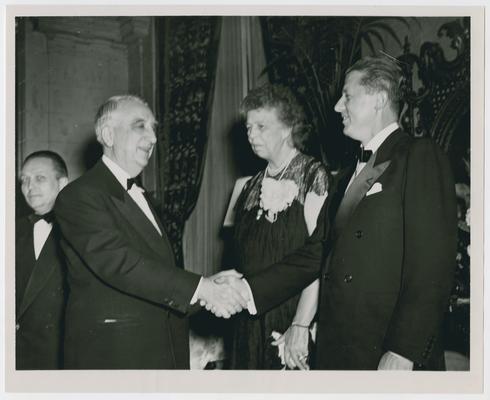Eleanor Roosevelt, center, stands behind Chief Justice Vinson and unidentified man during reception for Mrs. Roosevelt given by McCall's Magazine