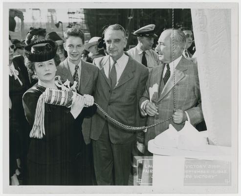 Page 5 of 38, Mrs. Vinson, with Fred M. and son at her side, ready to swing decorated champagne bottle