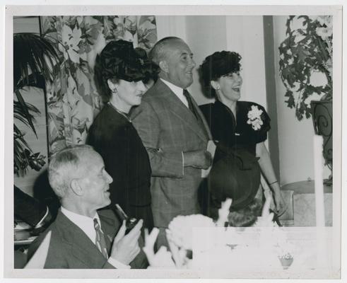 Page 29 of 38, unidentified man and two women at dinner celebration. Shot 1