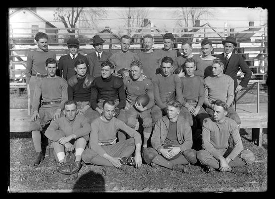 Football squad on bleachers, back left man with mustache and bushy hair