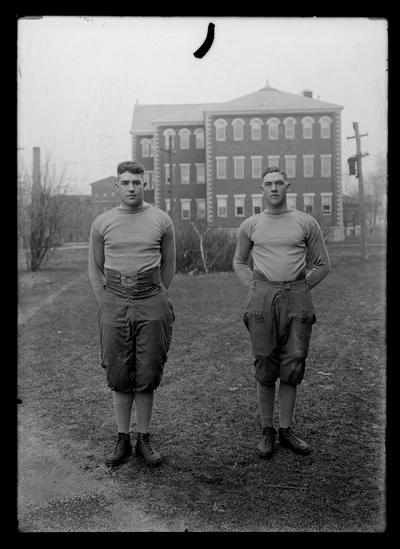 Football, two individuals: Dewey Downing, guard, Clay Downing, end, Miller Hall in background