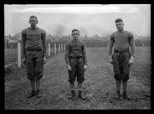 Football players in group of three: Rogers Moore, James Hedges, Eger Murphree, tackle