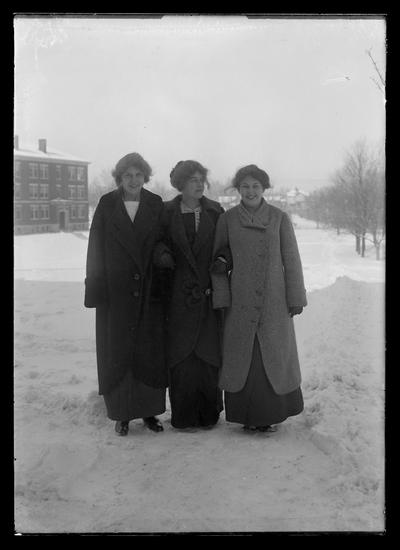 Three women students in long dresses to ankle, coats, no hats