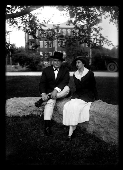 Man and young woman seated on stone wall in front of Anderson with Miller Hall in background