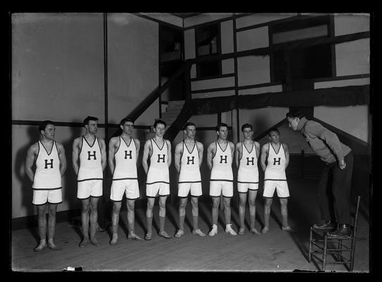 Crew of Brown of Havard, director standing on chair, eight men in gym suits