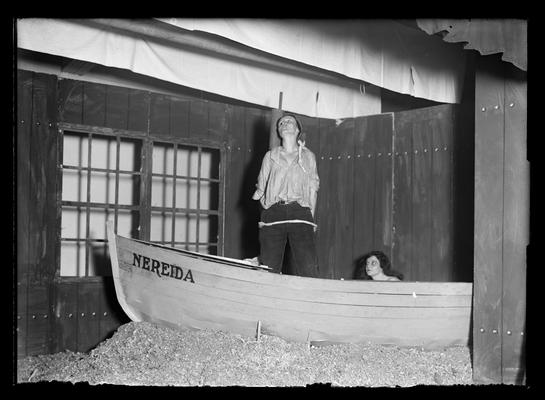 Scene from The Cat Boat, girl seated, boy standing in boat