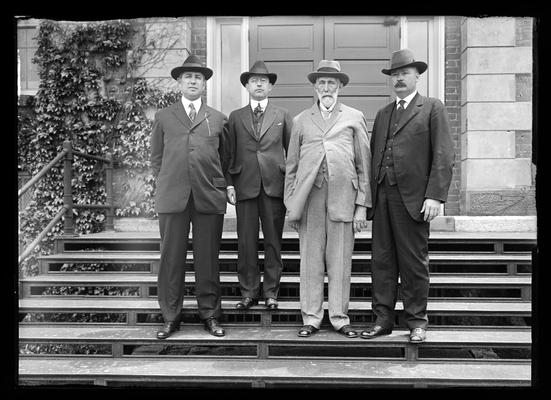 Four men on steps of Administration Building (Main Building), one short man, one with beard