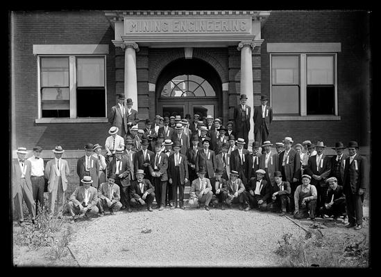 Mining group, large group of men with badges in front of Norwood Hall, some kneeling in front, President Barker near center of group on steps