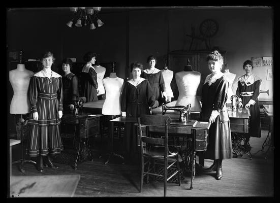 Sewing, all standing, members wearing dresses fitted on dress forms made to measure