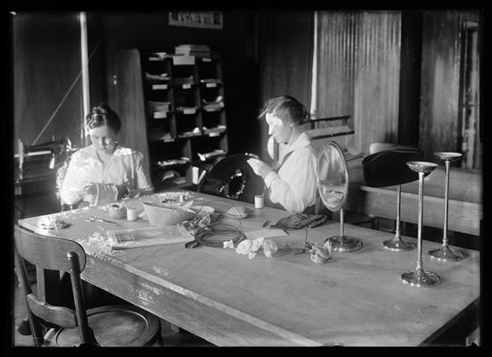 Millinery, two women, round mirror, hat stands