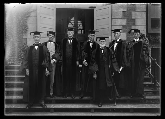 President Patterson and six men in robes on Administration Building (Main Building) steps, E.L. Powell, H.S. Barker, J.K. Patterson, A.J. Cochran, R.C. Stoll, two unidentified