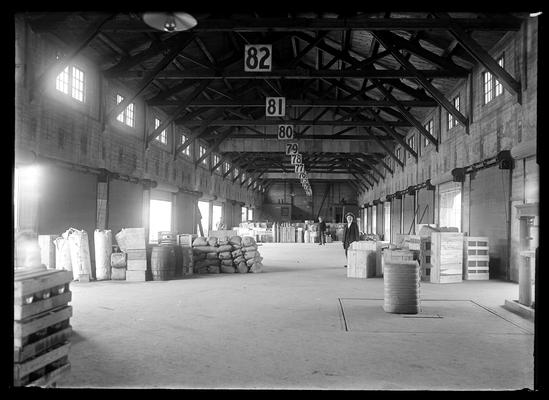 Interior of Freight Depot, overhead numbers from 82 down, three men in background