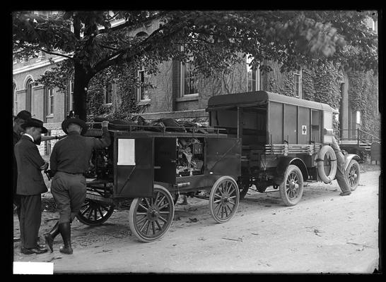 Red Cross truck, trailer, four men by north end of Administration Building (Main Building)