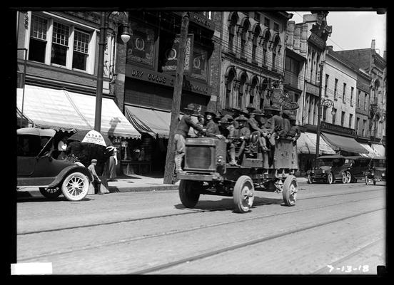 Truck with men on main street, passing Bassett's, Mitchell's, and Kresge's stores