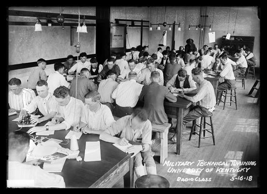 Men at several long tables in Physics room, notation Radio class