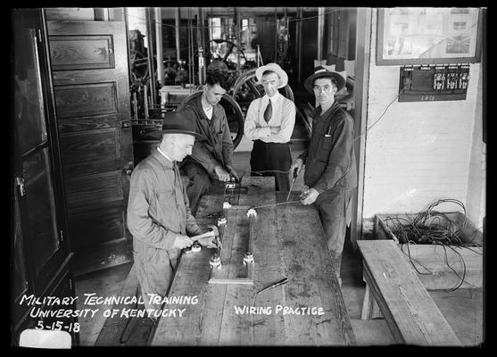 Instructor at end of table, three others, notation Wiring practice