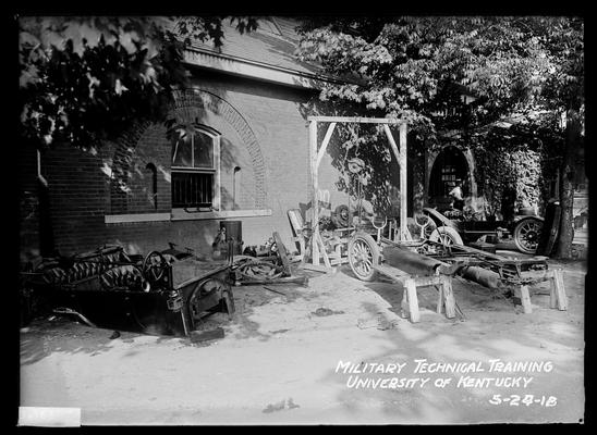 View outside of auto shop or armory, cars in various stages of assembly