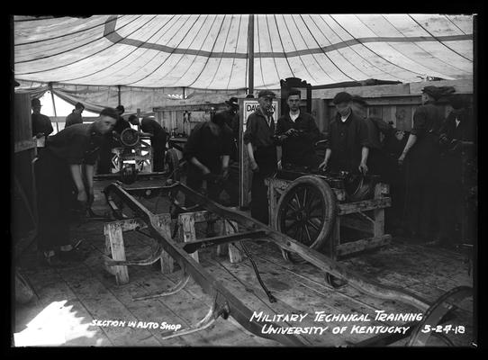 Men working under tent, notation Section in auto shop