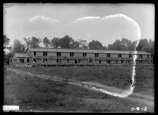 Distant view of first barracks, two men on roof near ladder