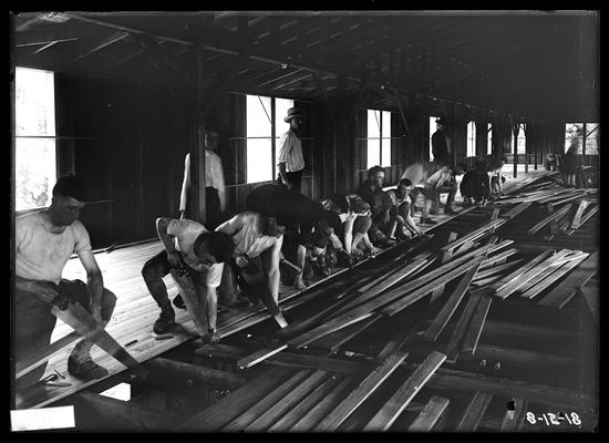 Carpenters at work on floor of barracks