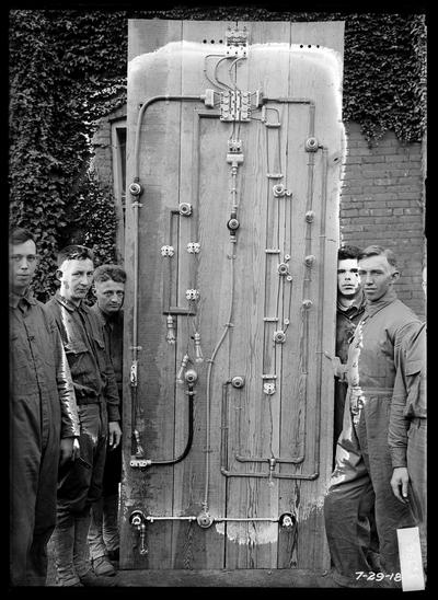 Electrical exercises in wiring mounted on large board, six men