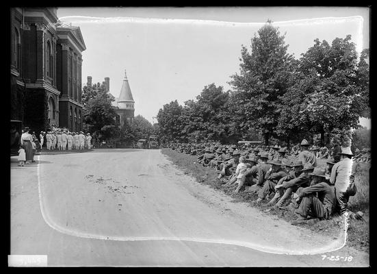 Army seated on ground facing Administration Building (Main Building), navy band in front of building, view looking south
