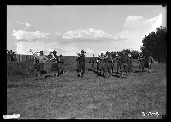 Marching on grass by side of track, fence to left, notation Detachment band