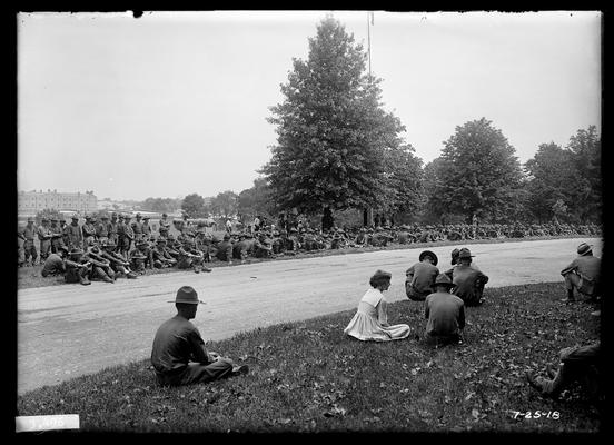Men seated on ground around driveway of University of Kentucky, some by Administration Building (Main Building), view looking north, listening to Navy band
