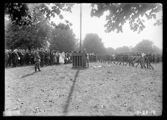 Piano by flag pole, people to left, notation Memorial services