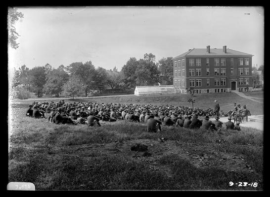 Group listening to speech, man standing on railroad memorial, Agricultural Building (Scovell Hall) in background