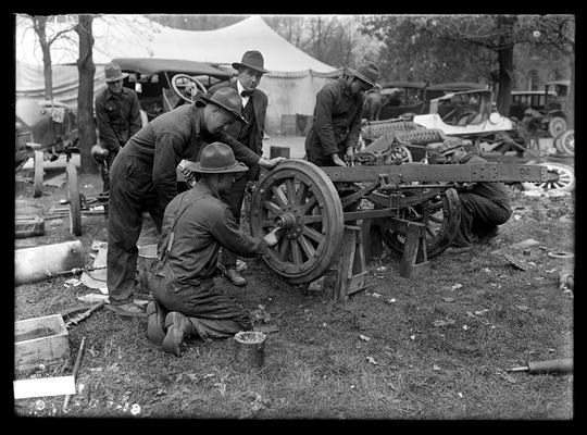 Men working on car or truck axel outside tent