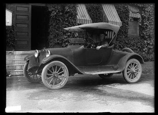 One seated car, driver in military uniform, in front of Mechanical Hall, 1918