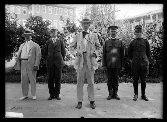 Five men with hats on: Dean F. Paul Anderson one step in front, D. Howard Peak, President Frank L. McVey, Commandant H.N. Royden, Captain Harding