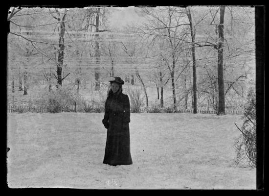 Young woman with hat in the yard, woodland in background