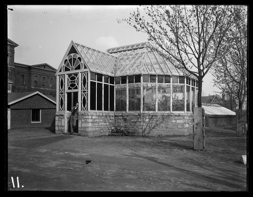 Greenhouse with heating plant to left, White Hall in left background, man in doorway