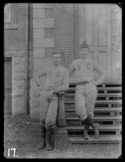 Football players, two on steps of Administration Building (Main Building), one with mustache