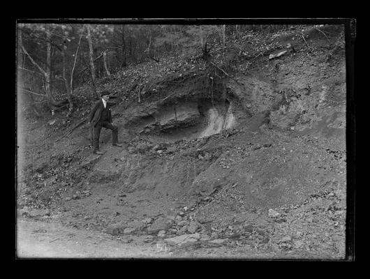 Man on hillside, odd geological formation or mound