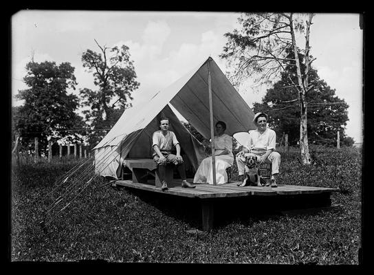 Man, woman, boy and dog in front of tent