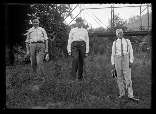 Three men with bridge in background