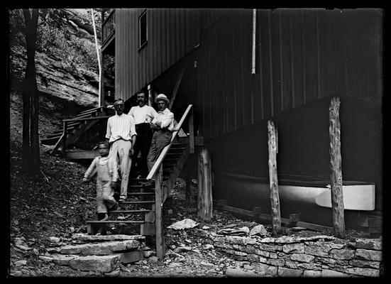 Three men, boy on steps of camp