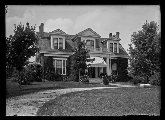 Two story, dormers, vine covered, awnings