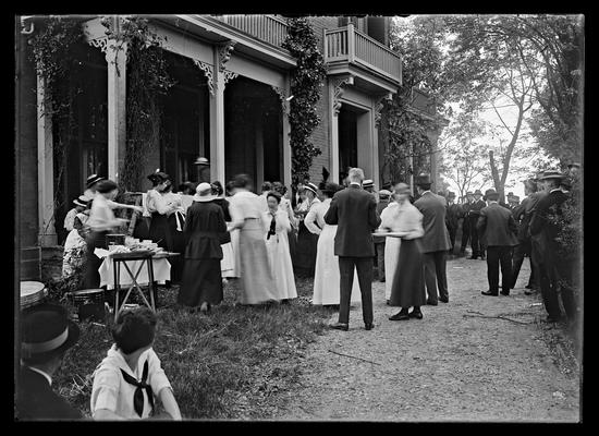 Gathering of people in front of house, food being served