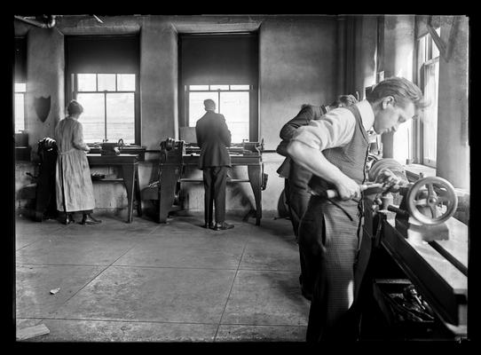 One woman, several young men, lathes around wall