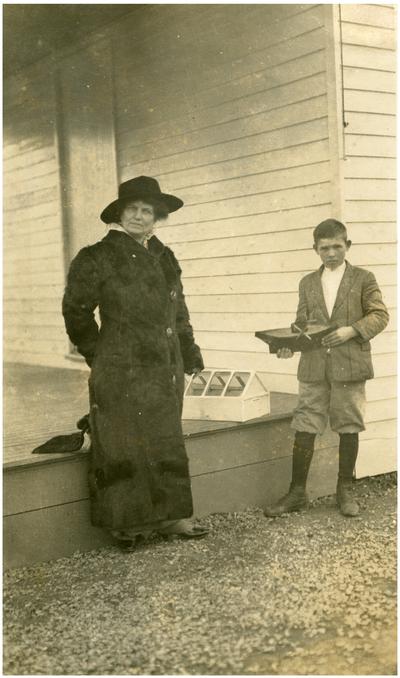 Portrait of Nannie Faulconer (1865?-1941), standing with a Lisle student who is holding a toy boat