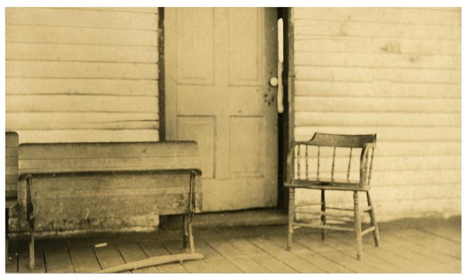 Chair and desk on the front porch of the Locust Grove school house. Handwritten on verso, Locust Grove-bad equipment
