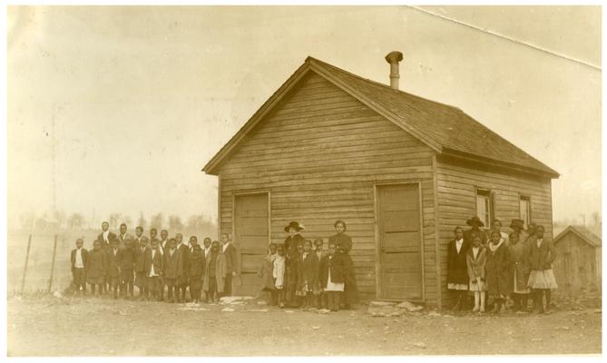 Group portrait of Maddoxtown students and Nannie Faulconer (1865?-1940) standing in front of the school house